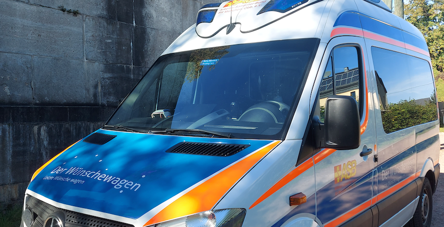 ASB-Wünschewagen neben einer steinernen Friedhofsmauer